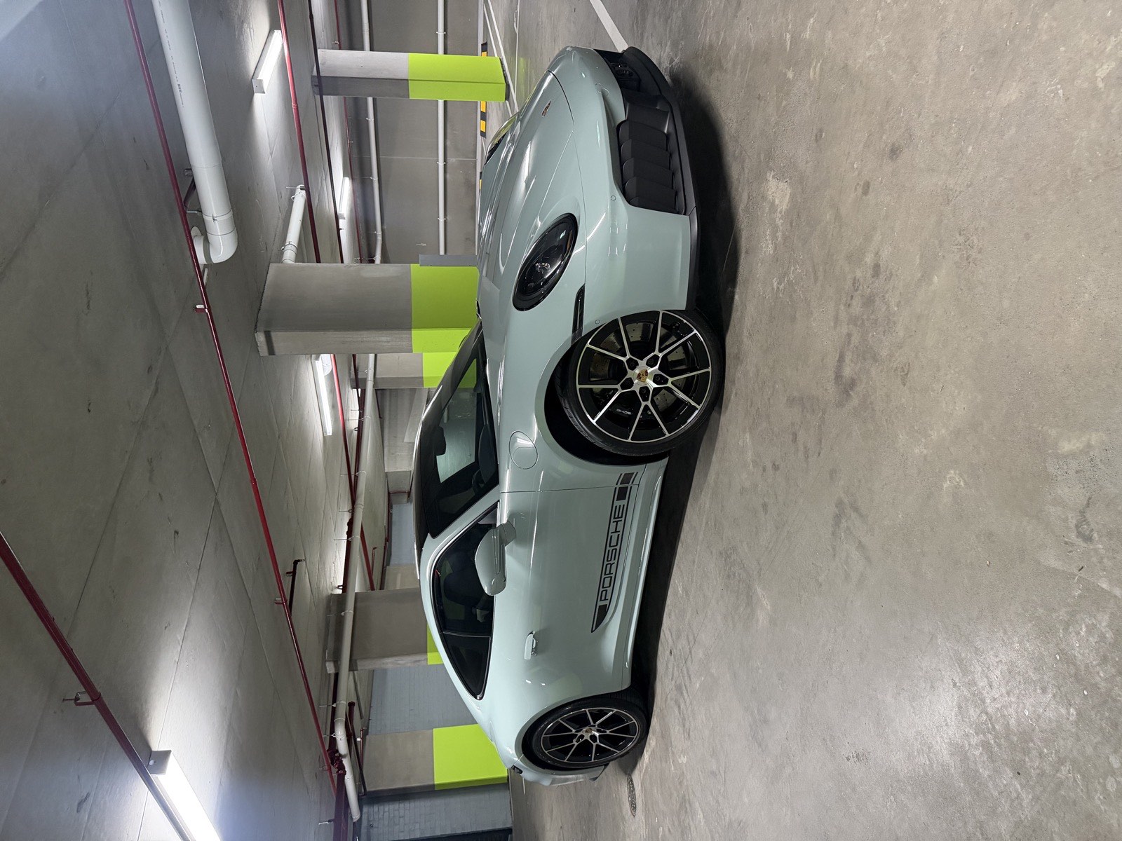 Silver Porsche coupe parked indoors, showing its side windows